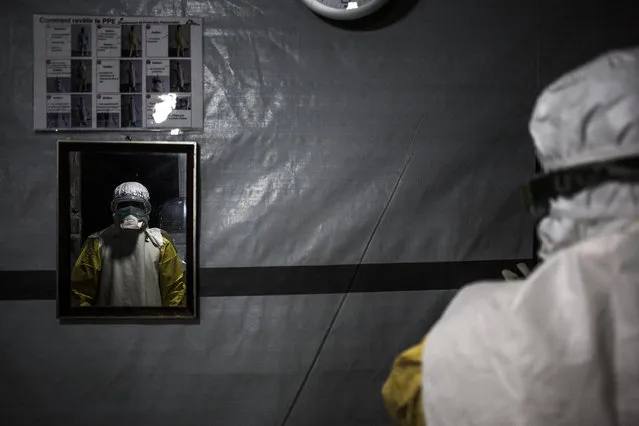 A health worker is seen in a mirror with his personal protective equipment (PPE) before entering the red zone of a MSF (Doctors Without Borders) supported Ebola Treatment Centre (ETC), where he will be checking up on patients on November 3, 2018 in Butembo, Democratic Republic of the Congo. The death toll from an Ebola outbreak in eastern Democratic Republic of Congo has risen to more than 200, the health ministry said on November 10, 2018. (Photo by John Wessels/AFP Photo)