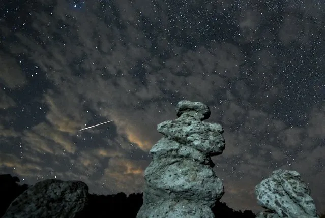 A long exposure photo shows meteor streaks crossing the night sky over the stone dolls in Kuklica, Republic of North Macedonia, 13 August 2023. The Perseid meteor shower occurs every year in August when the Earth passes through debris and dust of the Swift-Tuttle comet. (Photo by Georgi Licovski/EPA/EFE)
