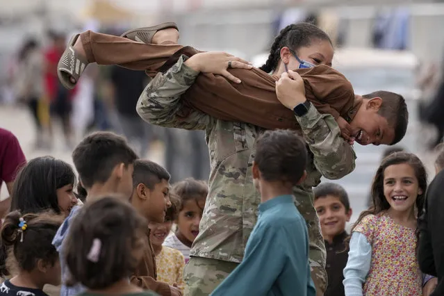 An U.S. soldier plays with recently evacuated Afghan children at the Ramstein U.S. Air Base, Germany, Tuesday, August 24, 2021.The largest American military community overseas housed thousands Afghan evacuees in an increasingly crowded tent city. (Photo by Matthias Schrader/AP Photo)