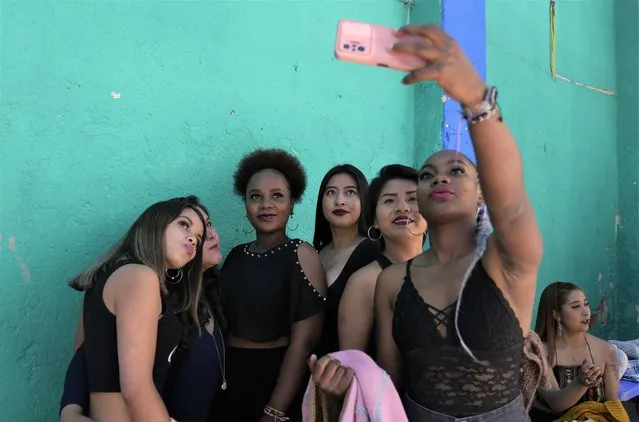 Inmates take a selfie while waiting their turns to model creations made by fellow inmates as they put on a fashion show at the Obrajes women's jail to mark Bolivian Women's Day in La Paz, Bolivia, Tuesday, October 11, 2022. (Photo by Juan Karita/AP Photo)