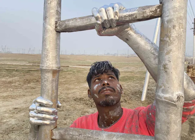 A man works on a structure for the upcoming “Magh Mela” festival in Prayagraj, in the northern Indian state of Uttar Pradesh, India. Tuesday, December 26, 2023. Thousands of people take holy dips at the confluence of the rivers Ganges, Yamuna and the mythical Saraswati during the month-long fair that begins later this month. (Photo by Rajesh Kumar Singh/AP Photo)