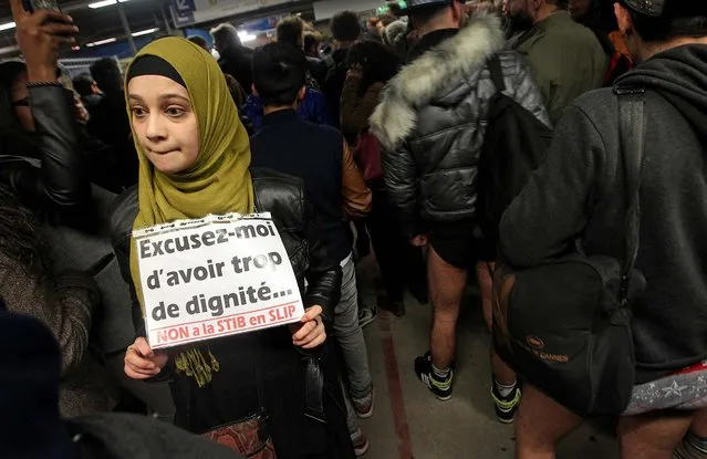 A woman holds a sign that reads: “Excuse me to have too much dignity, no to the public Brussels transport in underwear”, as participants around her take part in the No Pants Metro Ride in Brussels. (Photo by Yves Logghe/Associated Press)