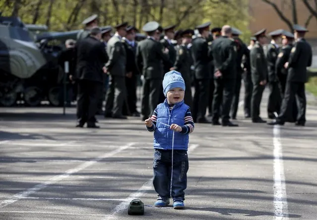 A boy plays with a toy after a graduation ceremony at the National University of Defence of Ukraine in Kiev, Ukraine April 24, 2015. (Photo by Gleb Garanich/Reuters)