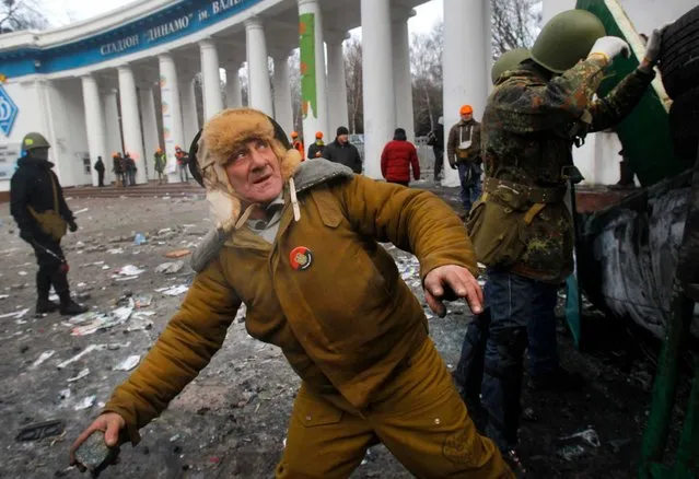 An elderly protestor prepares to throw a stone, during clashes with police, in central Kiev, Ukraine, Monday, January 20, 2014. (Photo by Sergei Grits/AP Photo)