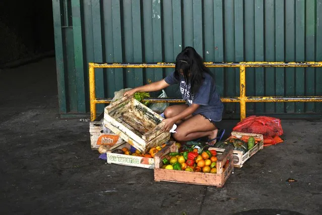 A youth collects discarded vegetables at a market on the outskirts of Buenos Aires, Argentina, Wednesday, January 10, 2024. (Photo by Natacha Pisarenko/AP Photo)