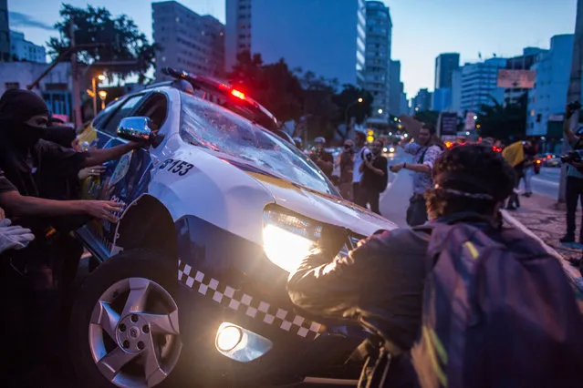 Protesters destroy a police vehicle during demonstrations against the staging of the upcoming 2014 World Cup on January 25, 2014 in Sao Paulo, Brazil. More than 100 protesters attended the demonstration. Demonstrations were planned for today in 36 Brazilian cities against the billions in spending for the games which begin June 12.(Photo by Victor Moriyama/Getty Images)