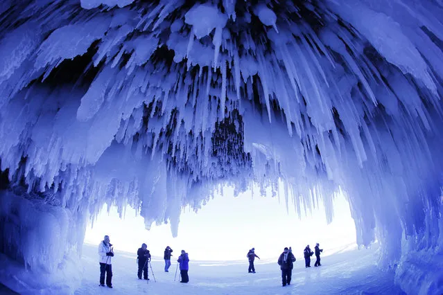In this February 2, 2014 photo, people visit the caves at  Apostle Islands National Lakeshore in northern Wisconsin, transformed into a dazzling display of ice sculptures by the arctic siege gripping the Upper Midwest. The caves are usually accessible only by water, but Lake Superior's rock-solid ice cover is letting people walk to them for the first time since 2009. (Photo by Brian Peterson/AP Photo/Minneapolis Star Tribune)