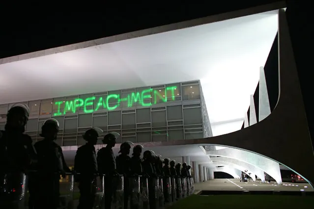 Soldiers stand guard outside the Planalto presidential palace where protesters have projected the word “Impeachment” on the building, as they call for the impeachment of Brazil's President Dilma Rousseff in Brasilia, Brazil, Monday, March 21, 2016. The political turmoil comes as Brazil prepares to host the Summer Olympics in August while struggling with an economic crisis and an outbreak of the Zika virus, which health experts believe may cause a devastating birth defect in newborns. (Photo by Eraldo Peres/AP Photo)