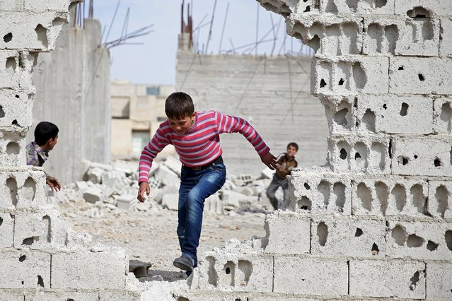 Boys play near rubble of damaged buildings in the rebel held besieged town of Douma, eastern Damascus suburb of Ghouta, Syria March 19, 2016. (Photo by Bassam Khabieh/Reuters)