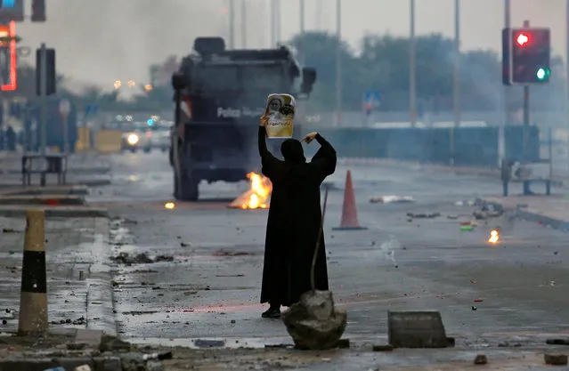A female protester holds a photo of Shi'ite scholar Isa Qassim as she confronts riot police armoured personnel carrier during a demonstration to mark the 6th anniversary of the February 14 uprising, in the village of Sitra, south of Manama, Bahrain February 14, 2017. (Photo by Hamad I Mohammed/Reuters)