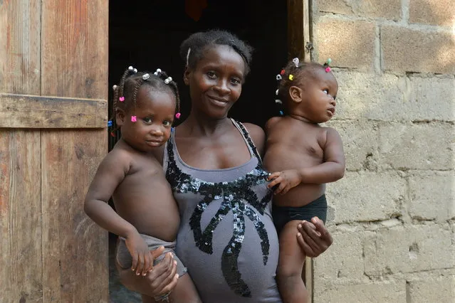 In this March 21, 2015 photo, Anise Germain holds her daughters Riguerlande, left, and Chrislove outside of her new subsidized rental home in the southeast Haitian town of Anse-a-Pitres. The Germain family is at the forefront of an effort to deal with a situation that was threatening to become another crisis for Haiti: an influx of people from across the border with the Dominican Republic amid an immigration crackdown. (Photo by David McFadden/AP Photo)