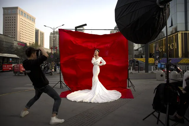 In this Thursday, March 28, 2019, file photo, a woman in wedding attire poses for a photo portrait along a busy street in Xi'an in northwestern China's Shaanxi Province. One of the ancient capitals of China, Xi'an is home to the world-renowned Terracotta Warriors. (Photo by Mark Schiefelbein/AP Photo)