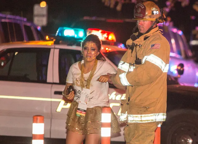 A firefighter assists an injured student after a stage collapsed during a student event at Servite High School in Anaheim, Calif., Saturday, March 8, 2014. Authorities said 30-40 people were taken to hospitals with mainly minor injuries. (Photo by Kevin Warn/AP Photo)