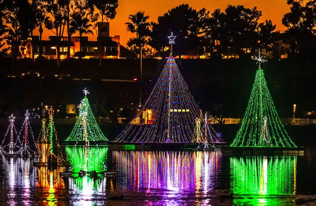 The glow of sunset along Pacific Coast Highway is the backdrop to holiday lighting reflecting off the water at Newport Dunes Waterfront Resort's 31st annual Lighting of the Bay lighting display in Newport Beach on Monday, November 29, 2021. (Photo by Leonard Ortiz/The Orange County Register via AP Photo)