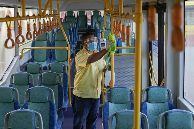 A bus driver sanitizes the interior of a bus before passengers' boarding at Larkin bus station in Johor Bahru, Malaysia, Monday, November 29, 2021. Malaysia and Singapore partially reopen their borders Monday for fully vaccinated citizens and some others, after nearly two years of closure due to the pandemic that had stranded many Malaysians working in the neighboring city-state away from their families. (Photo by Vincent Thian/AP Photo)
