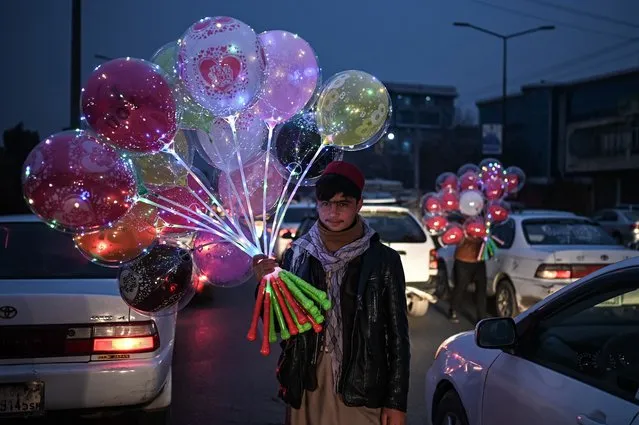 Boys sell balloons on a busy street in Kabul on December 25, 2021. (Photo by Mohd Rasfan/AFP Photo)
