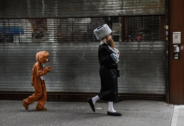 A boy wearing a costume walks behind his father as people celebrate the Jewish holiday of Purim in the Brooklyn borough of New York City, New York, U.S., February 26, 2021. (Photo by Stephanie Keith/Reuters)