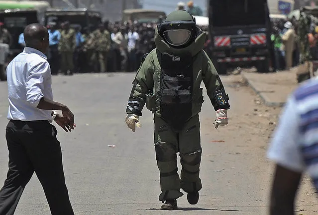 A Kenyan police bomb expert clad in a protective ballistic suit approaches the site of a suspected improvised explosive device, IED, on April 2, 2014 in Nairobi's increasingly restive Somali district of Eastleigh, a day after a prominent hardline Muslim cleric was shot dead in Mombasa. (Photo by Tony Karumba/AFP Photo)