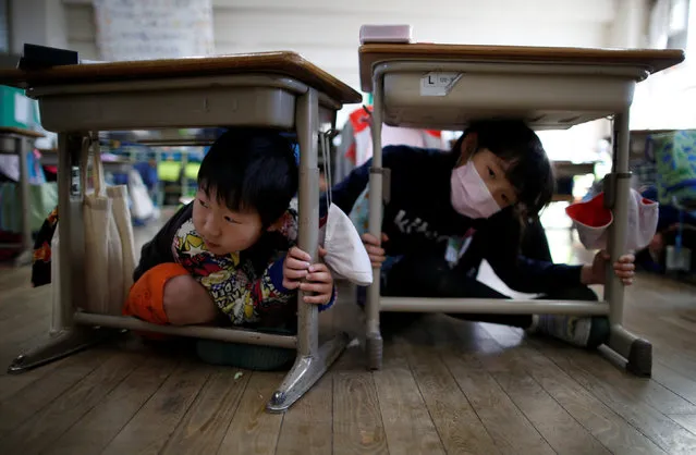 School children take shelter under desks during an earthquake simulation exercise in an annual evacuation drill at an elementary school in Tokyo, Japan March 10, 2017, a day before the six-year anniversary of the March 11, 2011 earthquake and tsunami disaster that killed thousands and set off a nuclear crisis. (Photo by Issei Kato/Reuters)