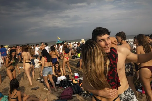 Teenagers dance late afternoon at the beach in Pinamar, Buenos Aires province, Argentina, Saturday, January 15, 2022. Amid a rebound in infections by the new Omicron variant of COVID 19, thousands of vacationers in Argentina fill the beaches in one of the hottest summers in recent years. (Photo by Rodrigo Abd/AP Photo)