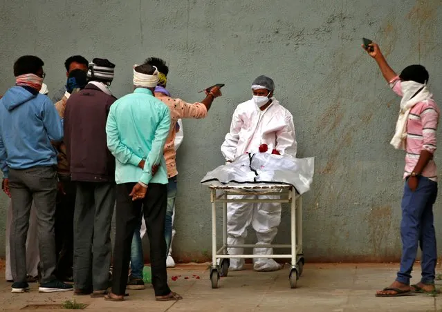 Men take photographs of the body of their relative after he died from the coronavirus disease (COVID-19) at a hospital in Ahmedabad, India, January 24, 2022. (Photo by Amit Dave/Reuters)