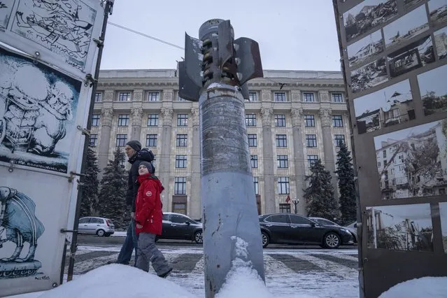 A man and his child walk past a Smerch rocket installed in front of regional administration as a part of a war exhibition in Kharkiv, Ukraine, Friday, January 28, 2022. Some people in Ukraine's second-largest city are preparing to fight back if Russia invades. The situation in Kharkiv, just 40 kilometers (25 miles) from some of the tens of thousands of Russian troops massed at the border of Ukraine, feels particularly perilous. (Photo by Evgeniy Maloletka/AP Photo)
