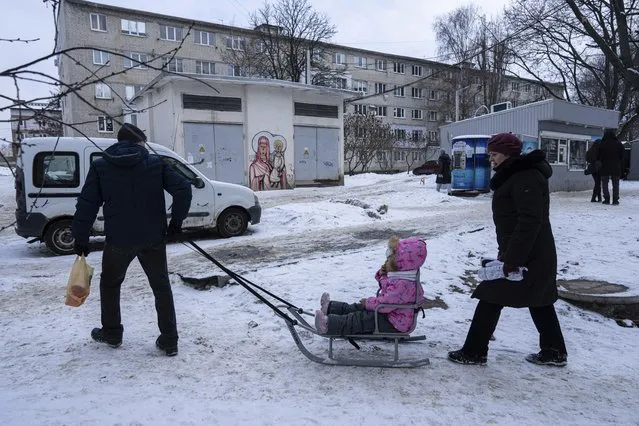 A man pulls a girl on a sleigh in a street in Kharkiv, Ukraine, Thursday, January 27, 2022. (Photo by Evgeniy Maloletka/AP Photo)