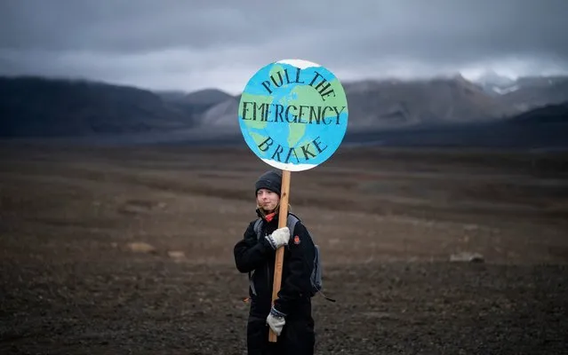 A girl holds a sign that reads “pull the emergency brake” as she attends a ceremony in the area which once was the Okjokull glacier, in Iceland, Sunday, August 18, 2019. With poetry, moments of silence and political speeches about the urgent need to fight climate change, Icelandic officials, activists and others bade goodbye to the first Icelandic glacier to disappear. (Photo by Felipe Dana/AP Photo)