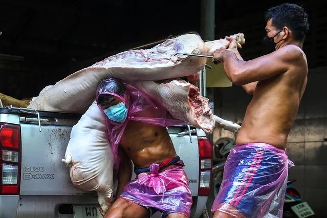 Butchers unload pieces of pork meat from a truck at a market as Thai authorities said on Tuesday that African swine fever had been detected in a surface swab sample collected at a slaughterhouse, in Bangkok, Thailand, January 11, 2022. (Photo by Chalinee Thirasupa/Reuters)