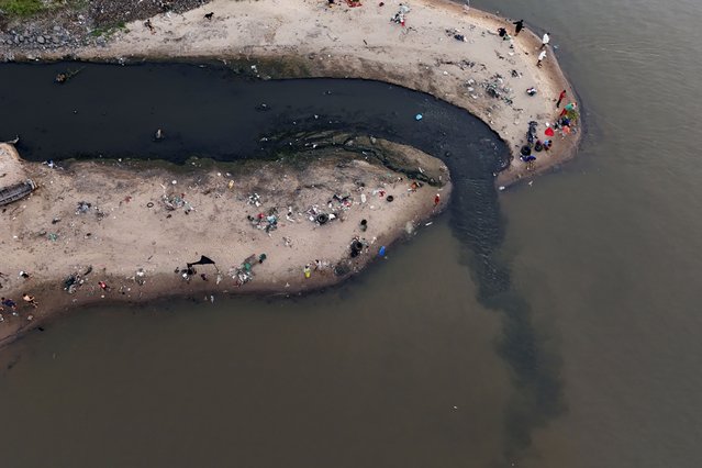 People fish next to drainage that flows into the Paraguay River in Asuncion, Paraguay, Sunday, January 28, 2024. (Photo by Jorge Saenz/AP Photo)