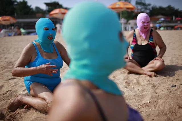 Women, wearing nylon masks, rest on the shore during their visit to a beach in Qingdao, Shandong province July 6, 2012. (Photo by Aly Song/Reuters)