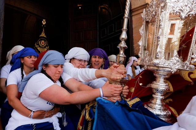 Women “costaleras” acting as “penitents” belonging to Cristo Resucitado y Nuestra Senora de Loreto brotherhood hold a structure in a ramp while others carry a statue of the Virgin Mary on a structure traditionally known as “paso”, as they leave a church during an Easter Sunday procession, the last day of Holy Week, in Ronda, Spain on April 9, 2023. (Photo by Jon Nazca/Reuters)