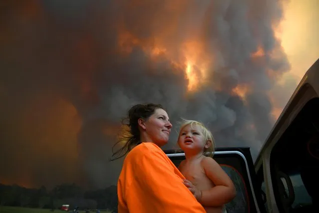 Sharnie Moren and her 18-month-old daughter Charlotte look on as thick smoke rises from bushfires near Nana Glen, near Coffs Harbour, Australia on November 12, 2019. There are more than 50 fires burning around the state of New South Wales, with about half of those uncontained. (Photo by Dan Peled/AAP Image via Reuters)