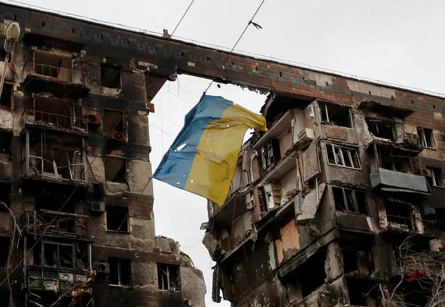 A view shows a torn flag of Ukraine hung on a wire in front an apartment building destroyed during Ukraine-Russia conflict in the southern port city of Mariupol, Ukraine on April 14, 2022. (Photo by Alexander Ermochenko/Reuters)