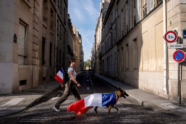 Alexandra Jezequel walks with her dog, Oban, draped in the flag of France, as she walks through the streets of Paris, France, Sunday, August 4, 2024, during the 2024 Summer Olympics. (Photo by David Goldman/AP Photo)