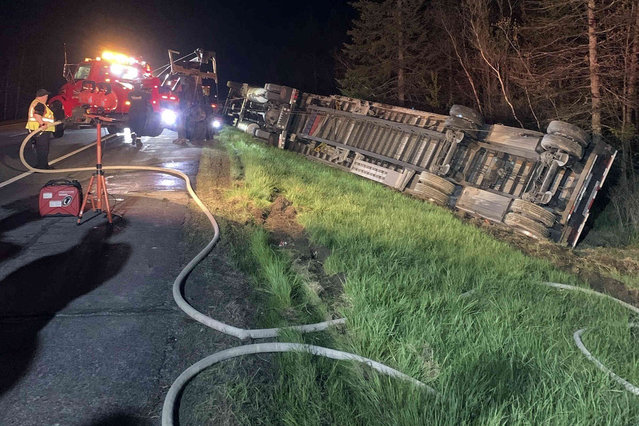 In this image provided by Maine State Police, emergency crews work to remove a tractor-trailer hauling 15 million bees to be used in pollinating the state's blueberry crops after it overturned on Interstate-95, Thursday evening, May 10, 2024, in Clinton, Maine. The driver was taken to a hospital and most of the bees were contained, officials said. (Photo by Maine State Police via AP Photo)