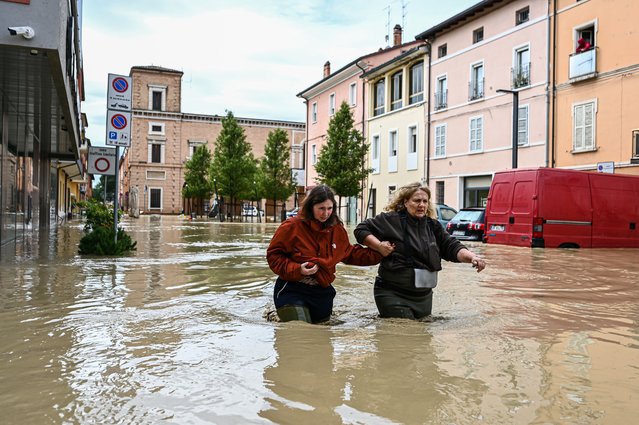 Pedestrians walk in a flooded street in Castel Bolognese, near Imola, Italy on May 17, 2023. At least three people were killed and thousands of others displaced after torrential rains poured over the northern Italian region of Emilia Romagna, local authorities said on Wednesday. (Photo by Piero Cruciatti/Anadolu Agency via Getty Images)