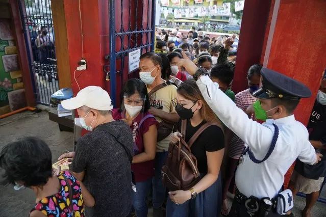 People rush to enter a school used as a polling center to vote during the opening of elections on Monday May 9, 2022 in Quezon City, Philippines. About 67 million registered voters will pick a new president, with Ferdinand Marcos Jr, son and namesake of the ousted dictator, leading pre-election surveys, and incumbent Vice President Leni Robredo, who leads the opposition, as his closest challenger. (Photo by Aaron Favila/AP Photo)