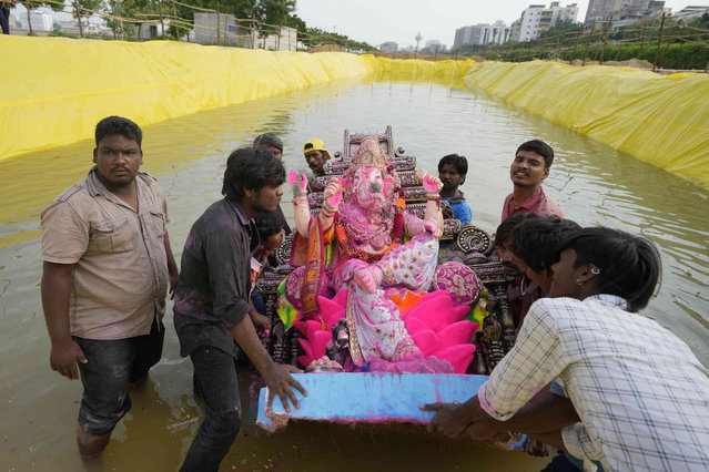 Devotees prepare to immerse an idol of elephant headed Hindu god Ganesha in an artificial pond at Sabarmati riverfront on sixth day of ten day long Ganesh Chaturthi festival in Ahmedabad, India, Thursday, September 12, 2024. (Photo by Ajit Solanki/AP Photo)