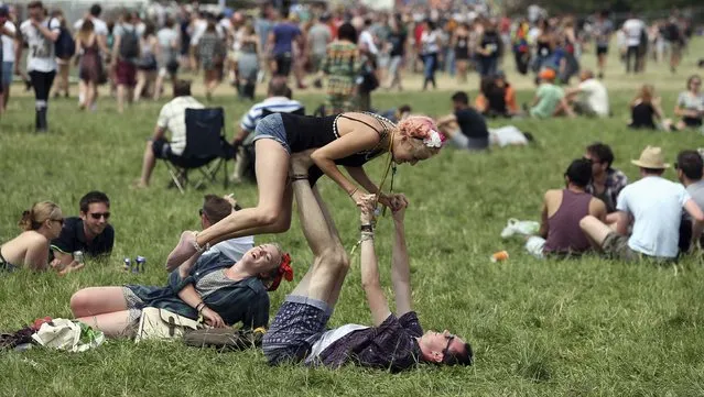 Festival goers are pictured in front of the Pyramid Stage at Worthy Farm in Somerset, on the second day of the Glastonbury music festival June 26, 2014. (Photo by Cathal McNaughton/Reuters)