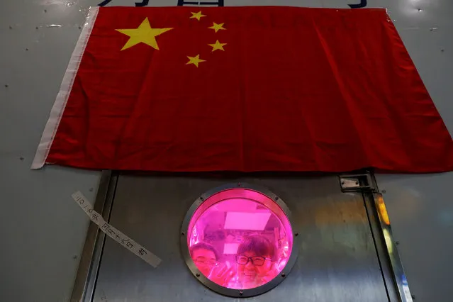 A volunteer waves to a member of staff from inside a simulated space cabin in which she temporarily lives with others as a part of the scientistic Lunar Palace 365 Project, at Beihang University in Beijing, China July 9, 2017. A group of four volunteers entered the Lunar Palace, a space of 160 square meters, China's first bioregenerative life-support base where they will live for next 200 days replacing another group who spent previous 60 days inside the simulated cabin testing how a life-support system works in a moon-like environment. (Photo by Damir Sagolj/Reuters)