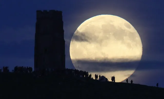 A full moon rises behind Glastonbury Tor as people gather to celebrate the summer solstice on June 20, 2016 in Somerset, England. Tonight's strawberry moon, a name given to the full moon in June by Native Americans because it marks the beginning of strawberry picking season, last occurred on the solstice on June 22, 1967 and it will not happen again on the summer solstice for another 46 years until June 21, 2062. (Photo by Matt Cardy/Getty Images)
