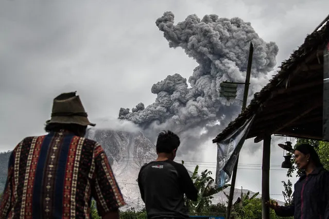 Residents stand to see as Mount Sinabung throws thick volcanic ash into the air, as seen from Tiga Pancur Villageon July 18, 2017 in Karo, Indonesia. Sinabung roared back to life in 2010 for the first time in 400 years. After another period of inactivity it erupted once more in 2013, and has remained highly active since. (Photo by Albert Damanik/Barcroft Images)
