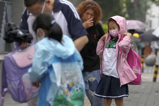 Students wearing face masks are accompanied by their relatives as they arrive at a primary school in Beijing, Monday, June 27, 2022. (Photo by Andy Wong/AP Photo)