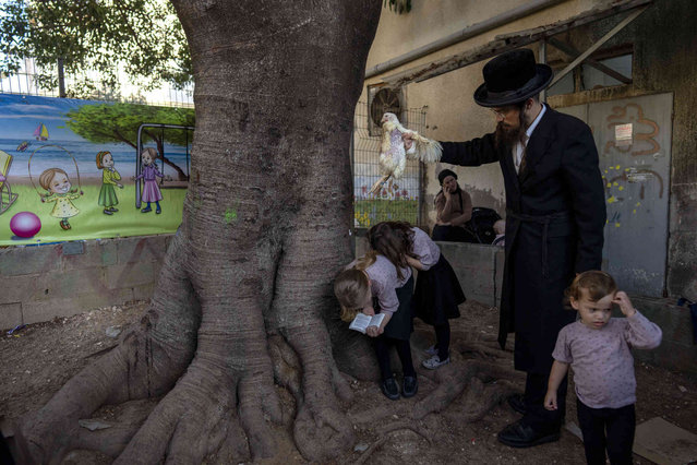 An ultra-Orthodox Jewish man swings a chicken over his daughter's head  in Bnei Brak, Israel, Thursday, October 10, 2024, as part of the Kaparot ritual a day before the Jewish holiday of Yom Kippur. (Photo by Oded Balilty/AP Photo)