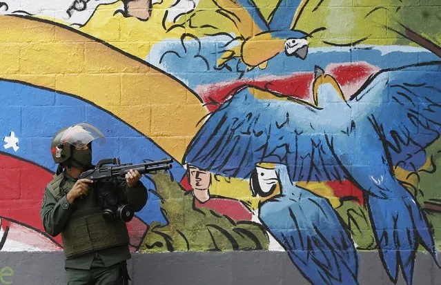 A National Guard points his weapon during clashes with anti-government demonstrations in the streets of Caracas, Venezuela, Thursday, July 20, 2017. Venezuelan President Nicolas Maduro and his opponents faced a crucial showdown Thursday as the country's opposition called for a 24-hour national strike. (Photo by Ariana Cubillos/AP Photo)