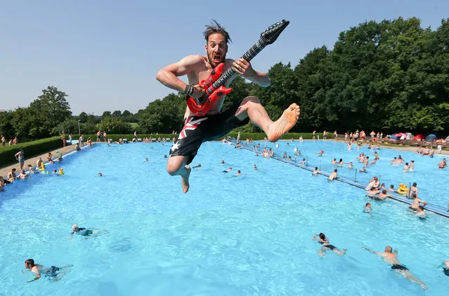 Benni, 33, from Dortmund jumps from the three-meter tower into the pool with an inflatable guitar in the swimming pool in Wacken, Germany,  August 1, 2014. About 75,000 visitors are expected to attend the heavy metal festival which runs from July 31 to August 2. (Photo by Axel Heimken/EPA)