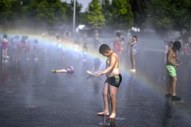 Children cool off in a fountain in a park by the river in Madrid, Spain, Wednesday, June 15, 2022. Spain's weather service says a mass of hot air from north Africa is triggering the country's first major heatwave of the year with temperatures expected to rise to 43 degrees Celsius (109 degrees Fahrenheit) in certain areas. (Photo by Manu Fernandez/AP Photo)