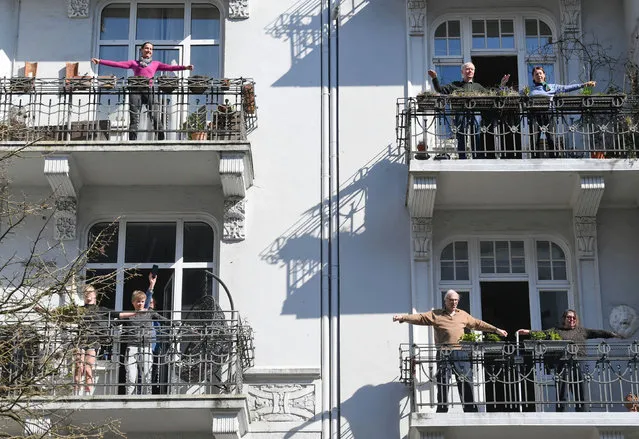 Residents exercise on their balconies according to the instructions of fitness trainer Patricio Cervantes during the spread of coronavirus disease (COVID-19) in Hamburg, Germany, March 26, 2020. (Photo by Fabian Bimmer/Reuters)