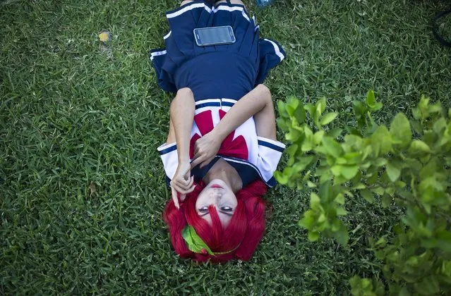Monserrat Gutierrez, dressed as vocaloid Kasane Teto, rests on a green lawn as she waits to compete in the individual cosplayer category costume contest, during the Yuukai Expo, in Managua, Nicaragua, Sunday, August 30, 2015. The expo is celebrating its second annual one day event for the lover of Japanese culture and anime. (Photo by Esteban Felix/AP Photo)
